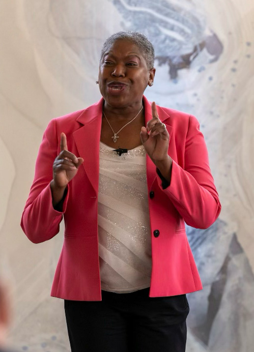 Michelle Perdue speaking and gesturing passionately in a pink jacket