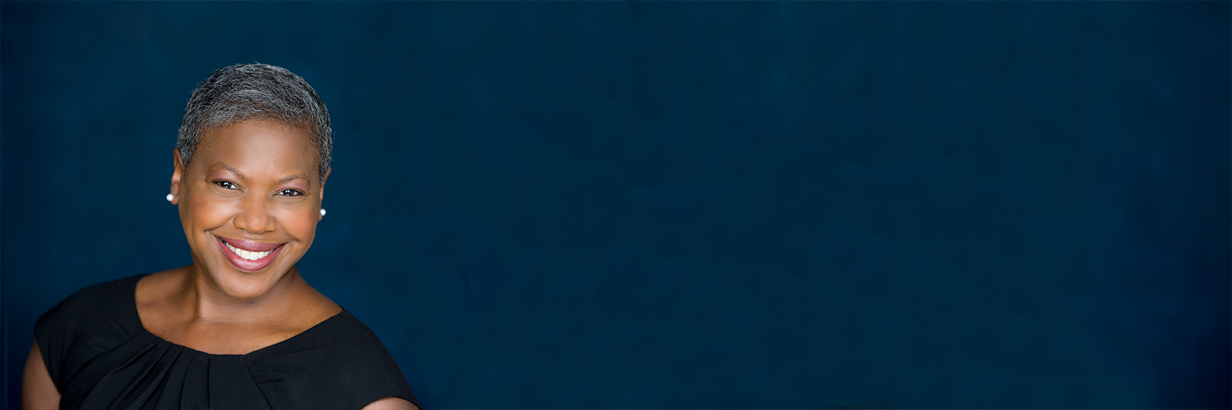 Headshot of Michelle Perdue smiling against a dark blue background